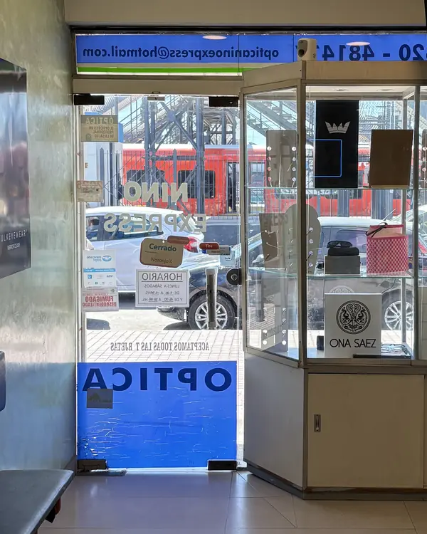Desde adentro del local, por la puerta de vidrio se ve un tren rojo parado en la estación