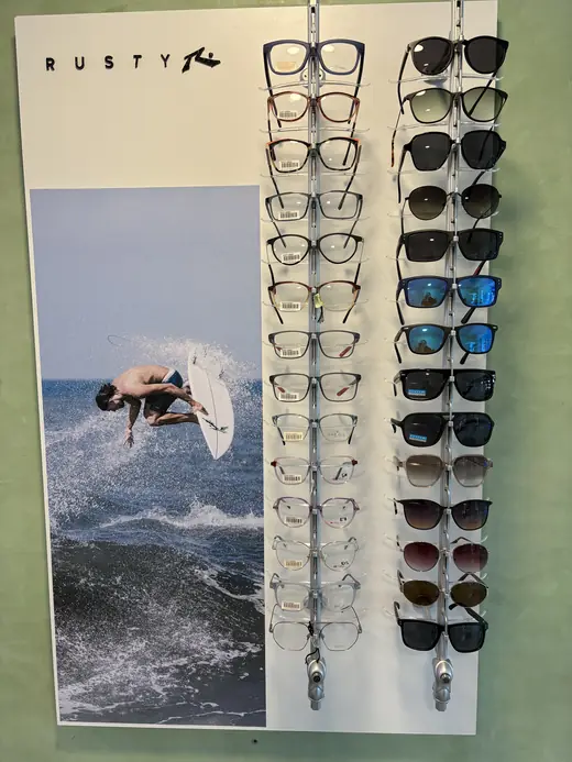 Exhibidor de Rusty con una foto de un surfista, armazones recetados y anteojos de sol