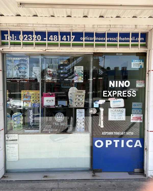 La vidriera desde la vereda, con Nino Express en la puerta y el cartel azul de Óptica abajo
